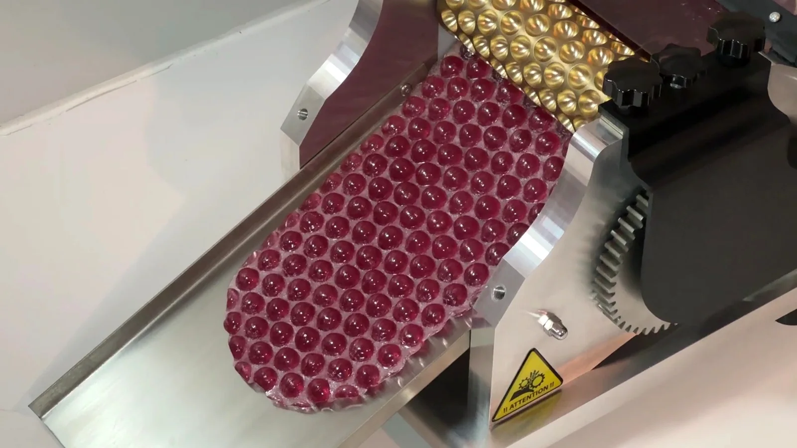 Bonbons rouges en sucre cuit à la sortie des rouleaux de la machine Atelier CAL